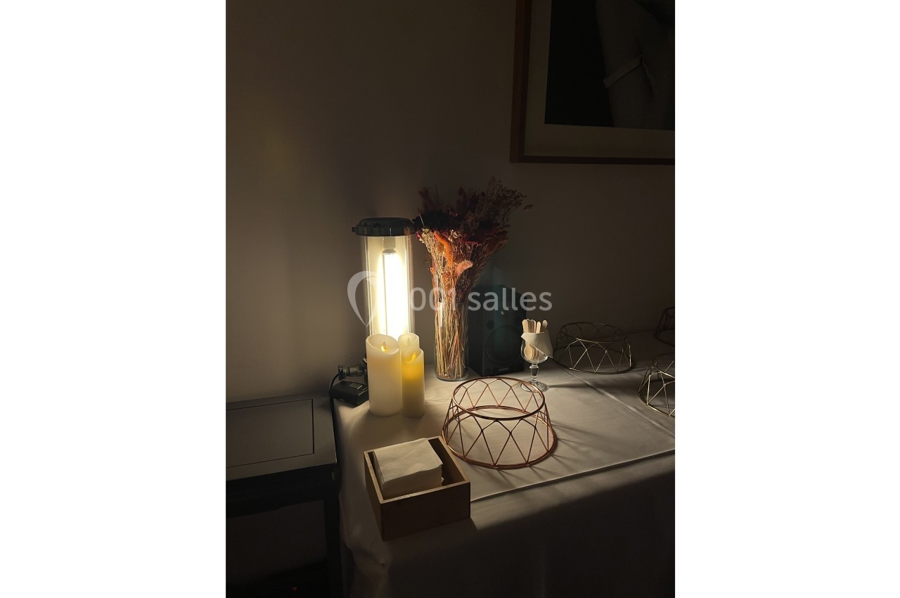 Location salle Paris 20 (Paris) - Studio 7 #12 Lampe allumée éclairant une table décorée avec des bougies, un bouquet séché et des objets en métal.