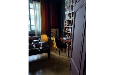 Miniature Location salle Paris 20 (Paris) - Studio 7 #29 Une chaise en bois et un mannequin près d'une porte ouverte donnant sur un couloir lumineux avec une rambarde en fer forgé.