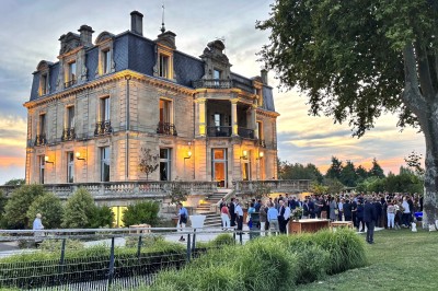 Montgolfière en cours de gonflage sur une pelouse, avec un manoir en arrière-plan et des arbres environnants.