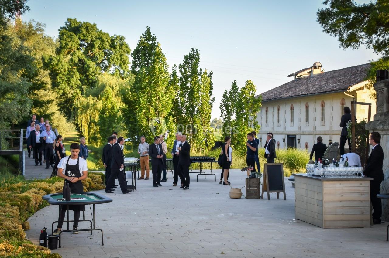 Des personnes en tenue élégante discutent et se rassemblent dans un espace extérieur près d'un bâtiment ancien.