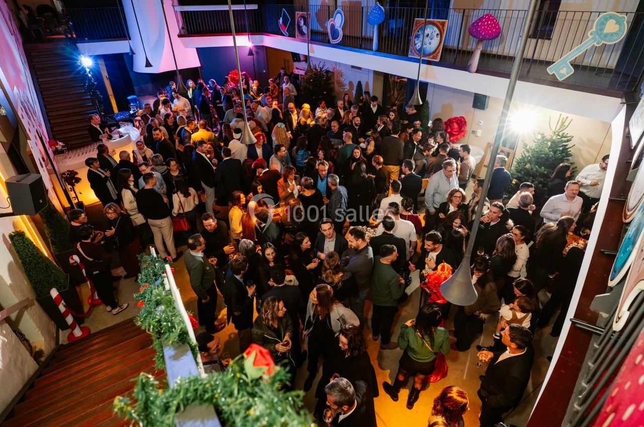 Groupe de personnes rassemblées dans un espace intérieur décoré pour une fête, avec des lumières et des éléments festifs.