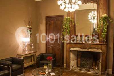 Tour en pierre entourée de végétation, avec bassin d'eau, chaises et tables en métal sur une terrasse ensoleillée.