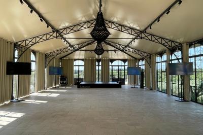 Tour en pierre entourée de végétation, avec bassin d'eau, chaises et tables en métal sur une terrasse ensoleillée.