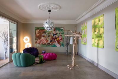 Tour en pierre entourée de végétation, avec bassin d'eau, chaises et tables en métal sur une terrasse ensoleillée.