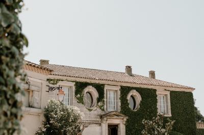 Tour en pierre entourée de végétation, avec bassin d'eau, chaises et tables en métal sur une terrasse ensoleillée.