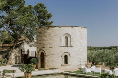 Tour en pierre entourée de végétation, avec bassin d'eau, chaises et tables en métal sur une terrasse ensoleillée.