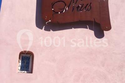 Salle lumineuse avec murs blancs et rouges, sol en carrelage beige, poutres apparentes et comptoir en pierre au fond.