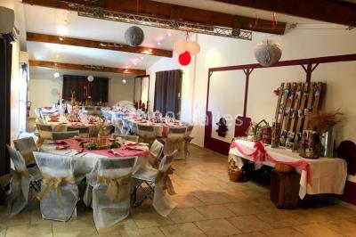 Salle lumineuse avec murs blancs et rouges, sol en carrelage beige, poutres apparentes et comptoir en pierre au fond.
