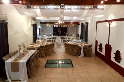 Salle lumineuse avec murs blancs et rouges, sol en carrelage beige, poutres apparentes et comptoir en pierre au fond.