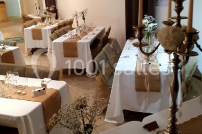 Salle lumineuse avec murs blancs et rouges, sol en carrelage beige, poutres apparentes et comptoir en pierre au fond.