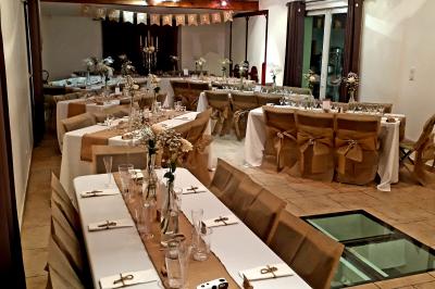 Salle lumineuse avec murs blancs et rouges, sol en carrelage beige, poutres apparentes et comptoir en pierre au fond.