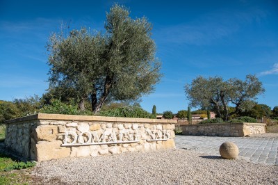 Salle lumineuse avec murs blancs et rouges, sol en carrelage beige, poutres apparentes et comptoir en pierre au fond.