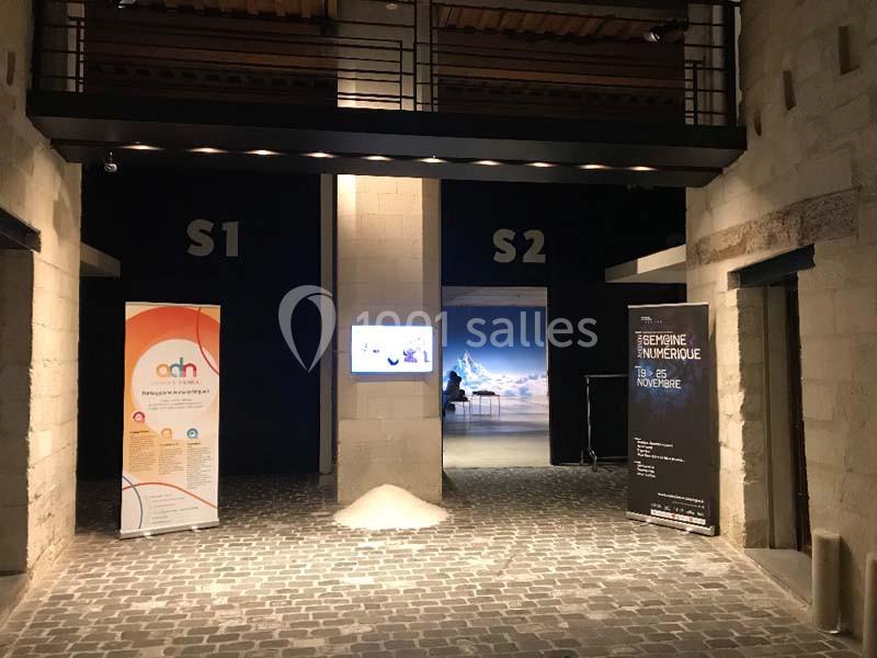 Location salle Avignon (Vaucluse) - Le Grenier à Sel #3 Entrée d'un espace d'exposition avec deux salles, affiches informatives et sol pavé sous un éclairage tamisé.