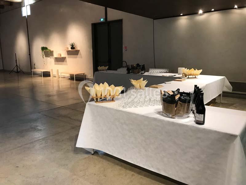 Location salle Avignon (Vaucluse) - Le Grenier à Sel #8 Tables dressées avec des verres, bouteilles et amuse-bouches dans une salle sobrement décorée et bien éclairée.