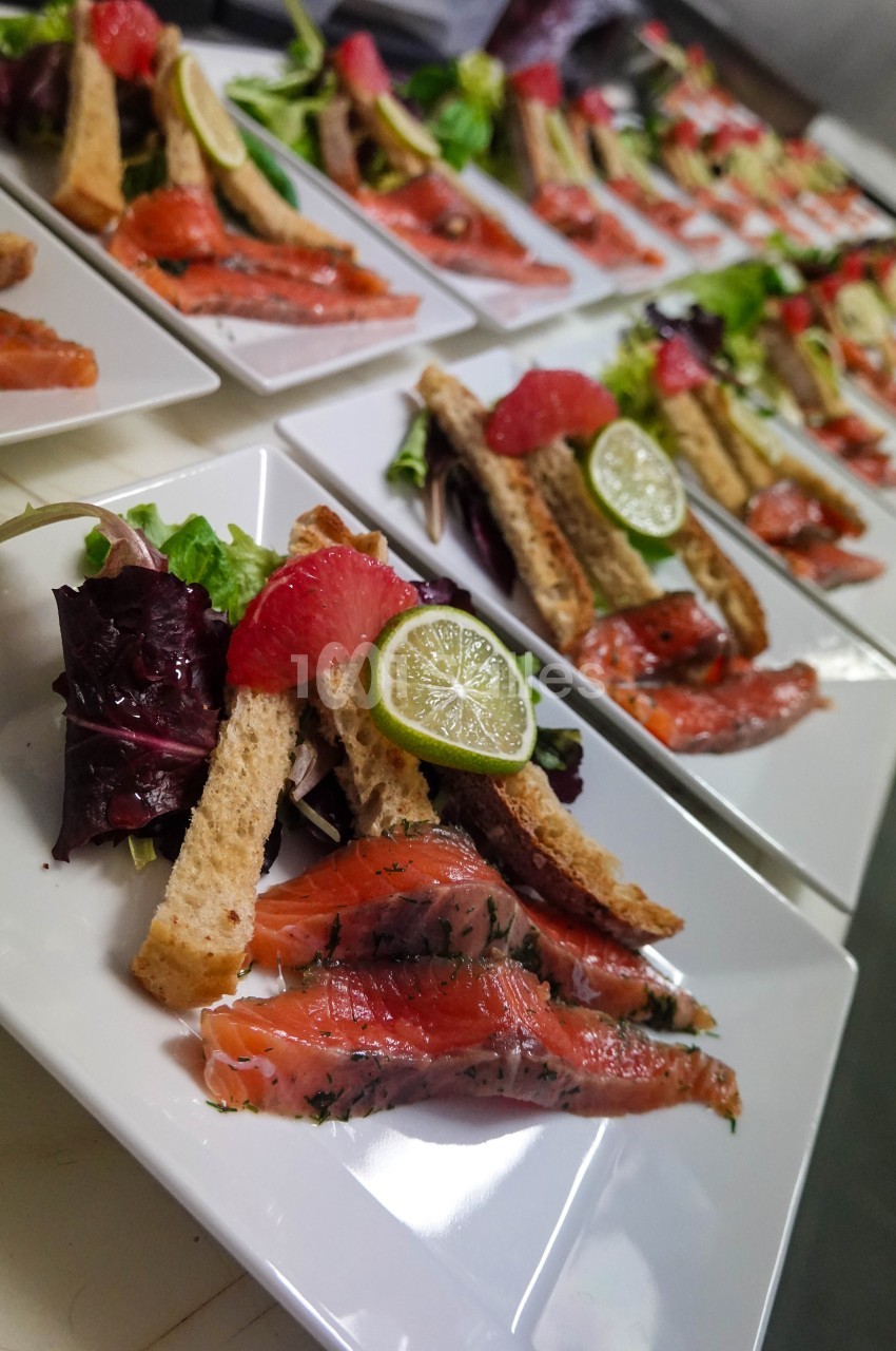 Assiettes de saumon mariné avec tranches de pain, salade verte, quartiers de pamplemousse et rondelles de citron vert.