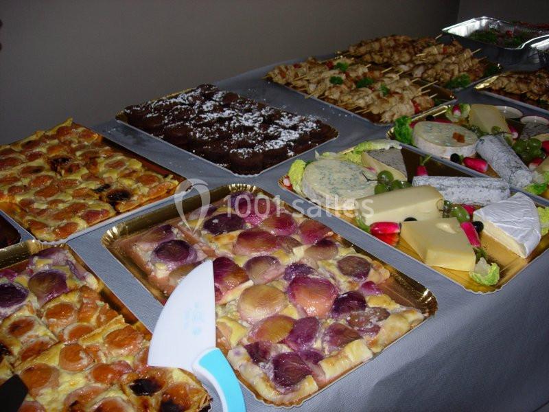 Table garnie de desserts variés, fromages, charcuteries et brochettes, présentés sur des plateaux pour un buffet.