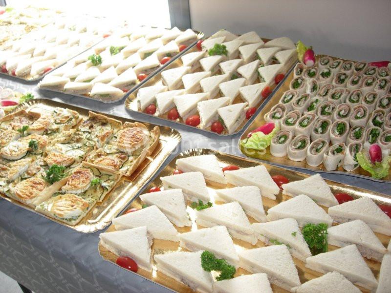 Plateaux de sandwichs variés, roulés et triangles, garnis de légumes et décorés de persil et radis.