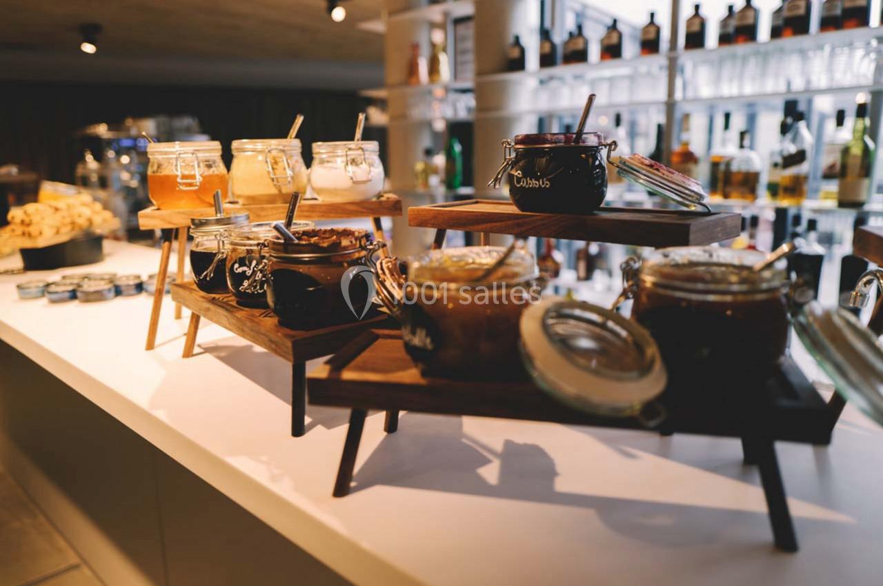 Location salle Montpellier (Hérault) - Hôtel Belaroïa #21 Pots de confitures variées disposés sur des étagères en bois dans un espace lumineux.