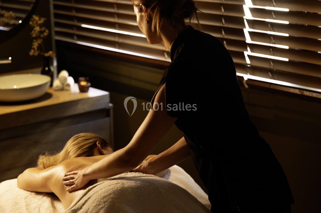 Location salle Montpellier (Hérault) - Hôtel Belaroïa #17 Une femme reçoit un massage relaxant dans une pièce tamisée avec des stores en bois et une ambiance apaisante.