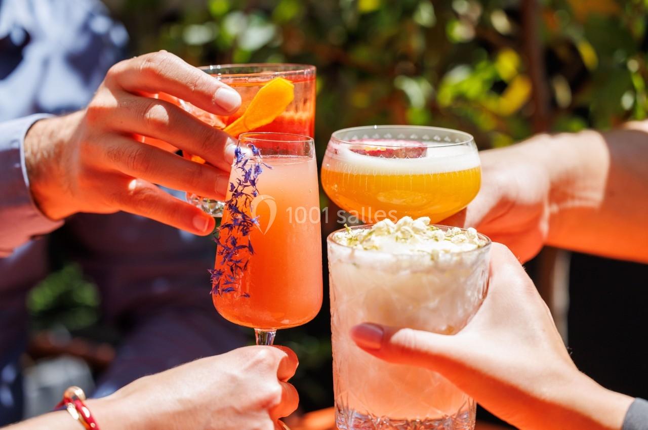Location salle Montpellier (Hérault) - Hôtel Belaroïa #19 Quatre personnes trinquent avec des cocktails colorés dans un cadre extérieur ensoleillé.