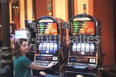 Une femme assise devant des machines à sous dans un casino, regardant l'écran de jeu.