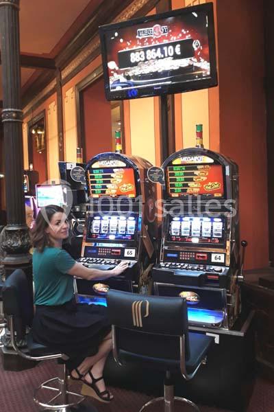 Une femme assise devant des machines à sous dans un casino, regardant l'écran de jeu.