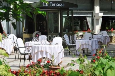 Salle de restaurant élégante avec tables dressées, chaises en bois sculpté et décor floral sur les murs et le sol.