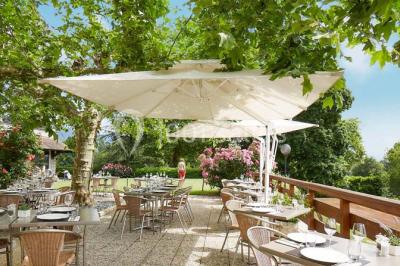 Salle de restaurant élégante avec tables dressées, chaises en bois sculpté et décor floral sur les murs et le sol.