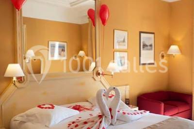 Salle de restaurant élégante avec tables dressées, chaises en bois sculpté et décor floral sur les murs et le sol.