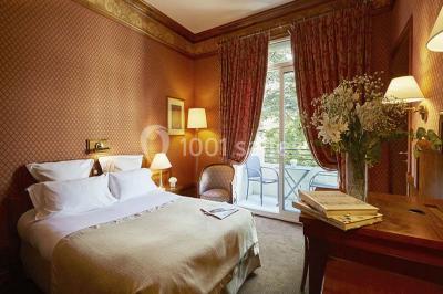 Salle de restaurant élégante avec tables dressées, chaises en bois sculpté et décor floral sur les murs et le sol.
