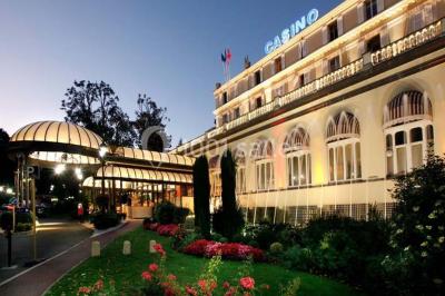 Salle de restaurant élégante avec tables dressées, chaises en bois sculpté et décor floral sur les murs et le sol.