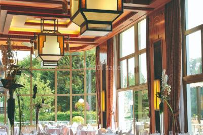 Salle de restaurant élégante avec tables dressées, chaises en bois sculpté et décor floral sur les murs et le sol.