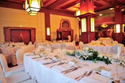 Salle de restaurant élégante avec tables dressées, chaises en bois sculpté et décor floral sur les murs et le sol.