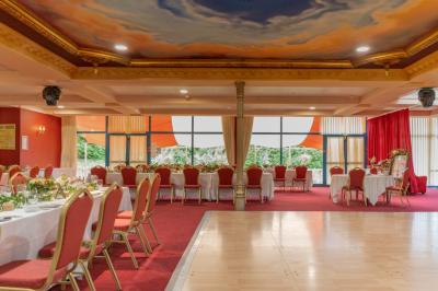 Salle de réception avec scène, piste de danse en bois, moquette rouge et plafond décoré d'une fresque.