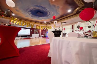 Salle de réception avec scène, piste de danse en bois, moquette rouge et plafond décoré d'une fresque.
