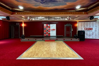Salle de réception avec scène, piste de danse en bois, moquette rouge et plafond décoré d'une fresque.