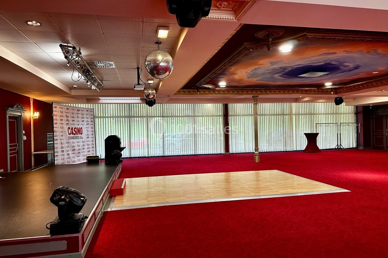 Salle de réception avec scène, piste de danse en bois, moquette rouge et plafond décoré d'une fresque.