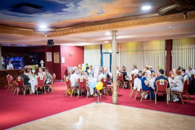 Salle de réception avec scène, piste de danse en bois, moquette rouge et plafond décoré d'une fresque.