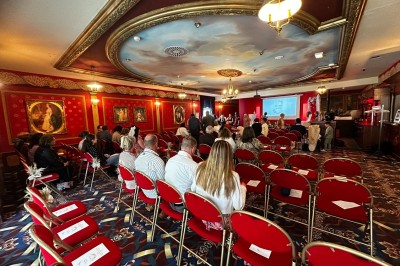 Salle de réception avec scène, piste de danse en bois, moquette rouge et plafond décoré d'une fresque.