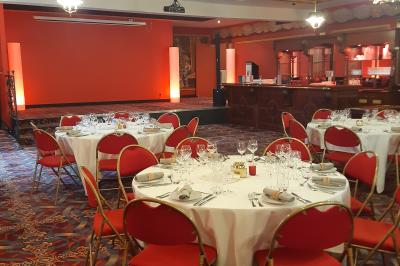 Salle de réception avec scène, piste de danse en bois, moquette rouge et plafond décoré d'une fresque.