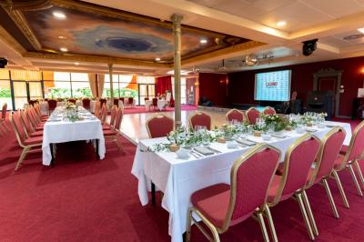 Salle de réception avec scène, piste de danse en bois, moquette rouge et plafond décoré d'une fresque.