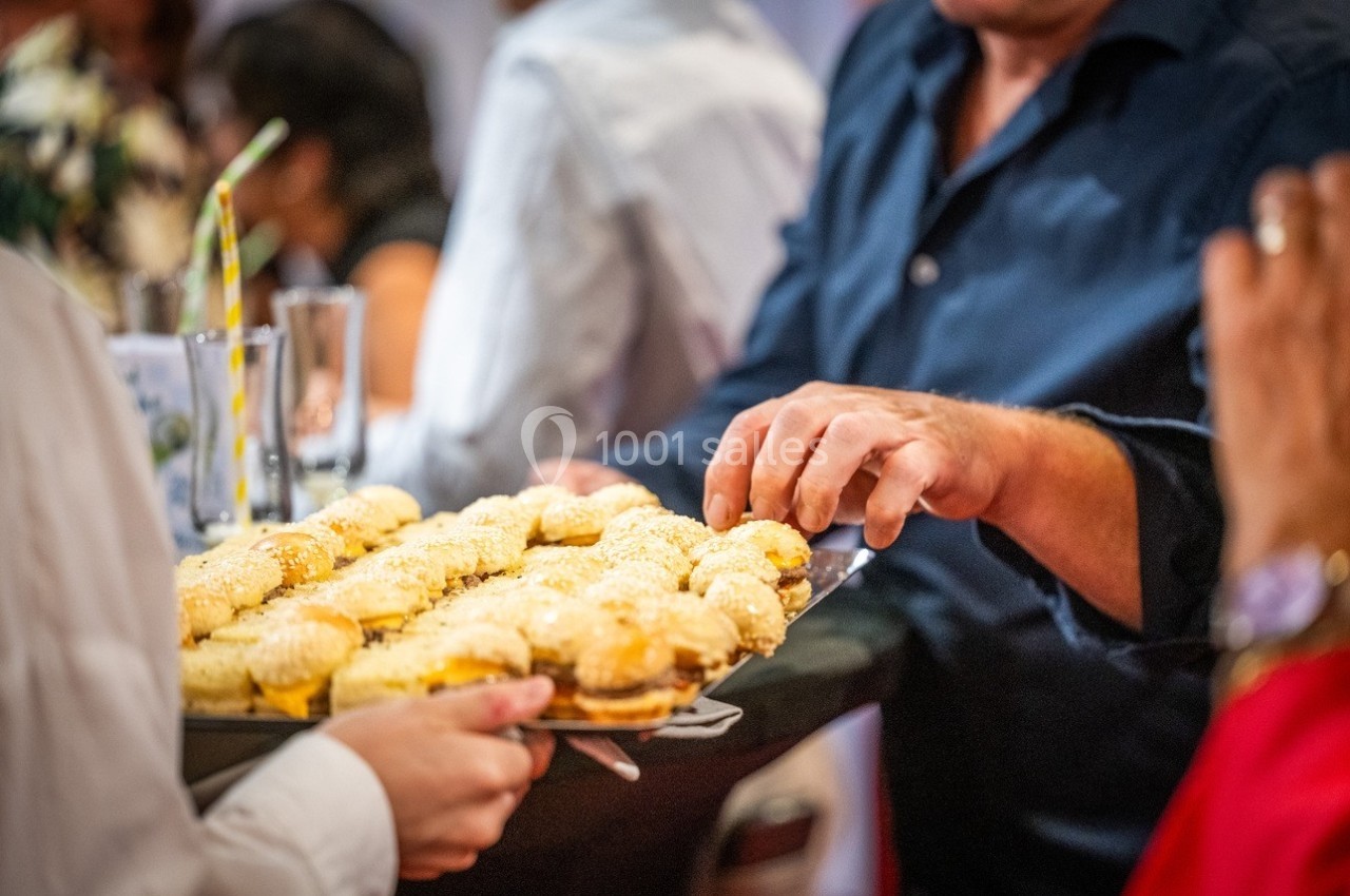 Une personne prend un mini-sandwich sur un plateau tenu par un serveur lors d'un événement.