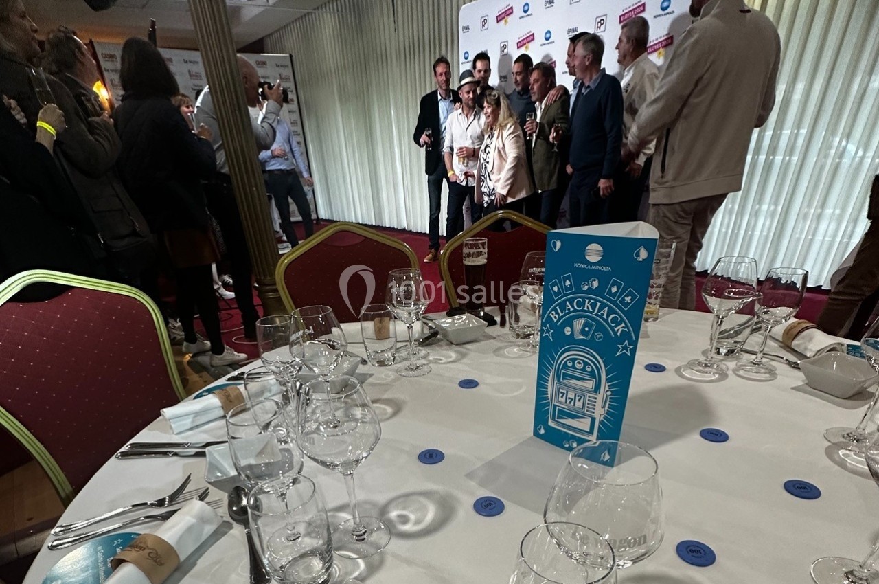 Groupe de personnes posant devant un mur de logos dans une salle, avec une table dressée au premier plan.