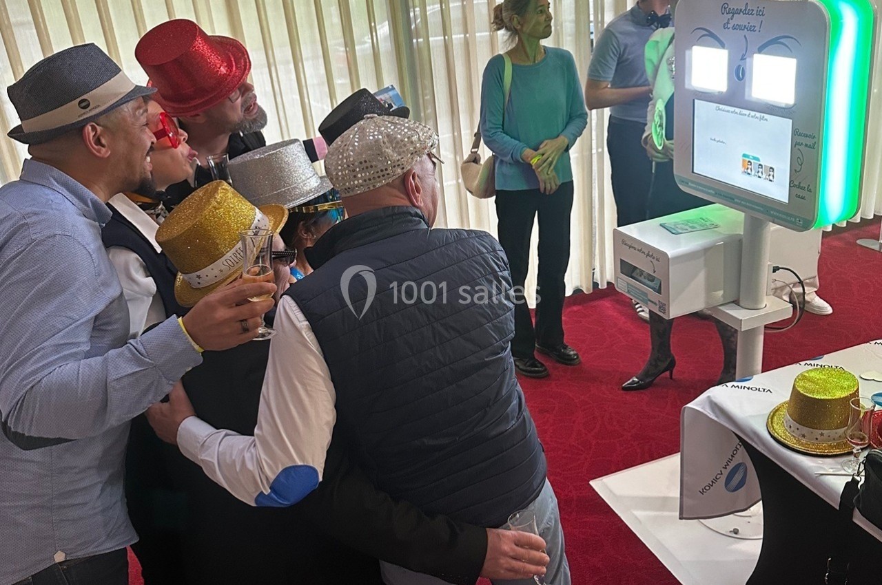 Des personnes portant des chapeaux festifs posent devant une borne photo interactive dans un espace intérieur.