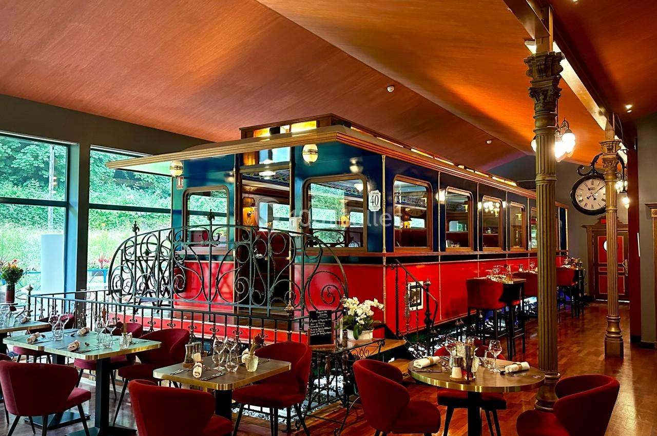 En voiture 40 au Restaurant Le Wagon Wagon de train rouge aménagé en salle de restaurant, entouré de tables dressées dans un décor chaleureux.