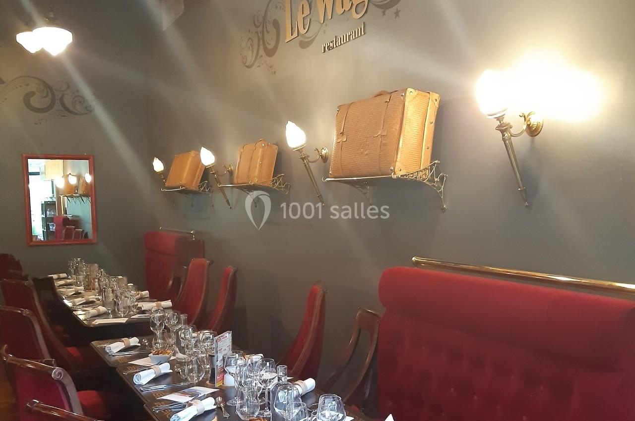 Le quai au Restaurant, idéal en petits groupes Salle de restaurant avec murs gris, banquettes rouges, tables dressées et valises décoratives sur des étagères murales.