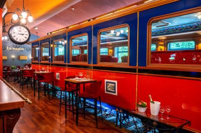 Miniature Le wagon du Restaurant Un barman réalise un spectacle de flair bartending avec des verres et un shaker dans une salle éclairée.