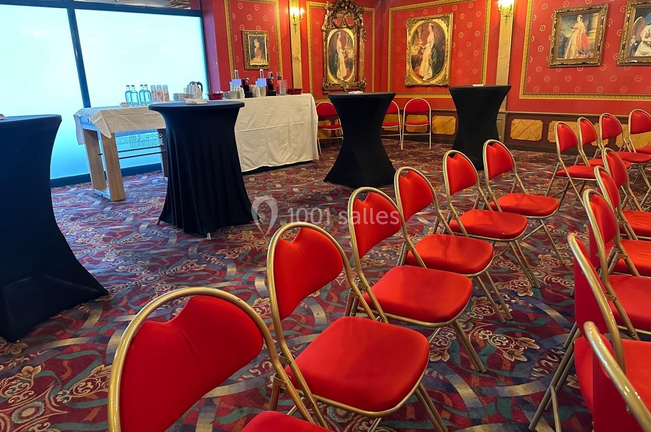 Pour vos réceptions et réunions dans un cadre atypique et intimiste Salle de réception avec chaises rouges alignées, tables hautes noires et buffet en arrière-plan.