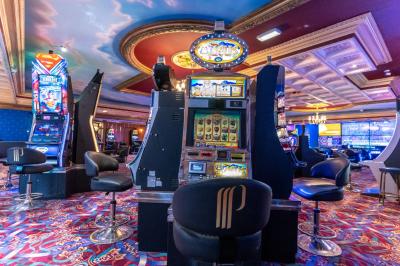 Miniature Salle des machines à sous du Casino Partouche de Plombières-les-Bains Un barman réalise un spectacle de flair bartending avec des verres et un shaker dans une salle éclairée.