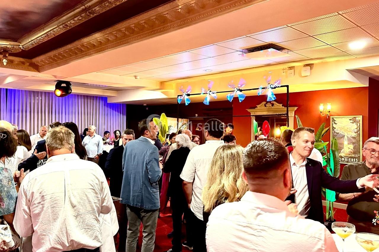 Soirée avec cocktail dinatoire Groupe de personnes rassemblées dans une salle décorée, discutant lors d'un événement ou d'une réception.